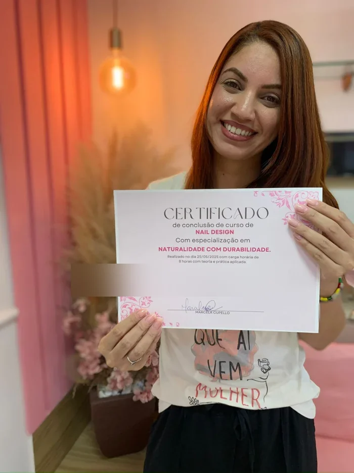 Aluna exibindo certificado de conclusão do curso de alongamento de unhas de gel com Marcela Cupello