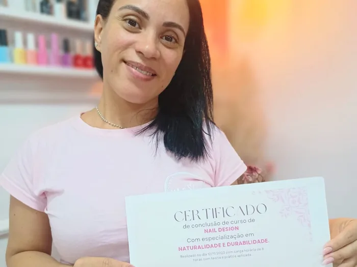Aluna exibindo certificado do curso de alongamento de unhas de gel com Marcela Cupello